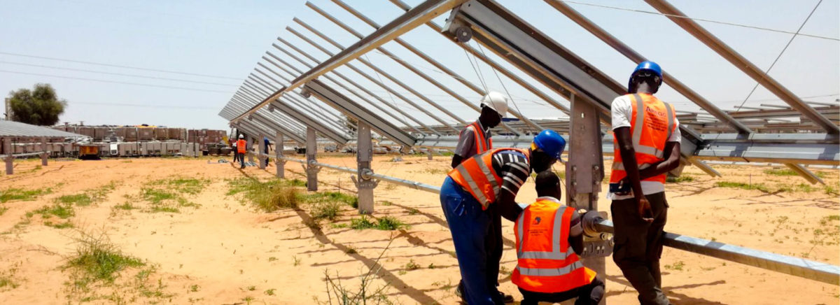 Quatre hommes travaillent sur la construction de la centrale solaire de Sakal au Sénégal.